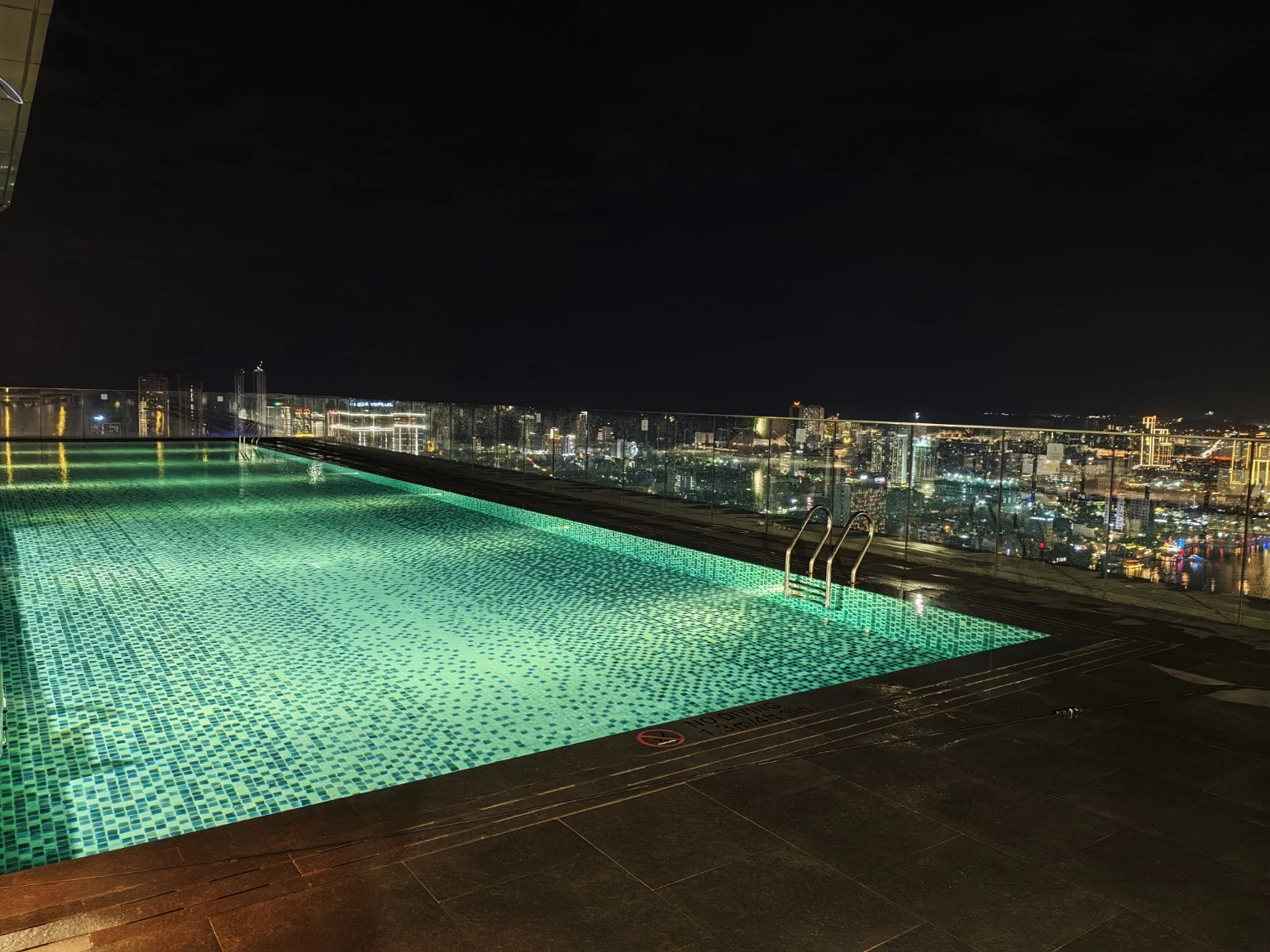 夜色中的屋頂泳池與城市天際線。